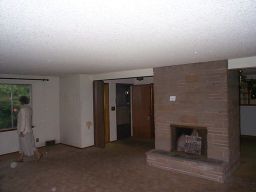 The living room, this picture from the other corner.  My mother is attempting to peer out some very dirty windows.